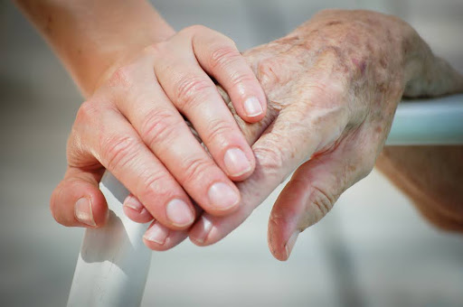 Young hand holding older adult hand.