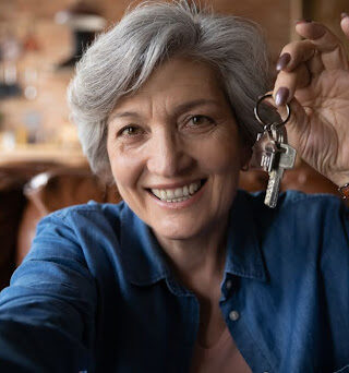 Older adult smiling and holding keys.