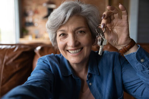 Older adult smiling and holding keys.