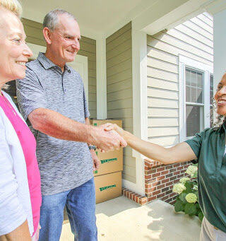 Older adult customers shake hands with a Bekins Van Lines employee.