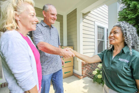 Older adult customers shake hands with a Bekins Van Lines employee.