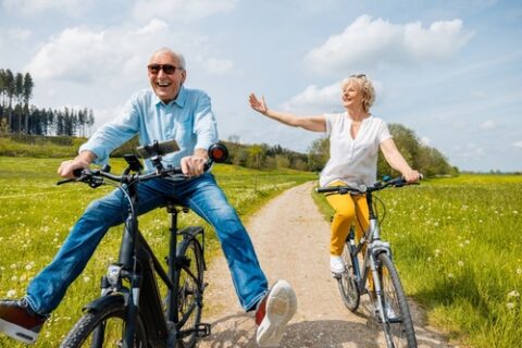 An older couple smiles while riding bikes