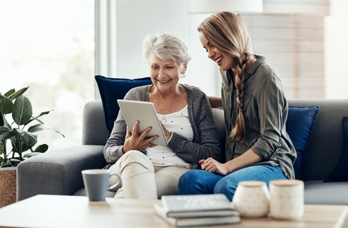 A young woman helps her grandmother with her smart tablet device.
