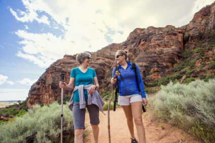 Two older woman  talk while hiking in the desert.