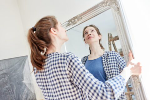 A woman moves a decorative antique mirror.