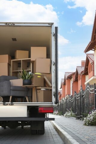 An open moving truck is parked alongside a residential street.