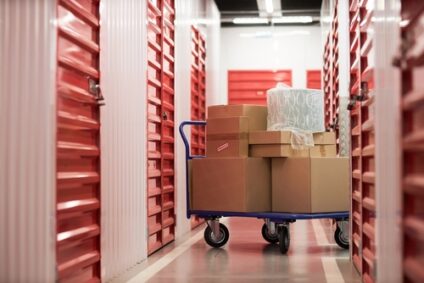 A cart full of moving boxes in the hallway of a storage unit facility.