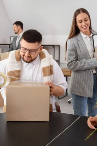 A group of employees packs up their office into boxes.