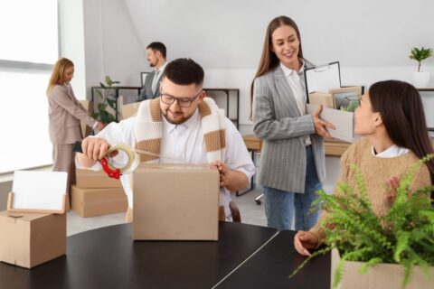 A group of employees packs up their office into boxes.