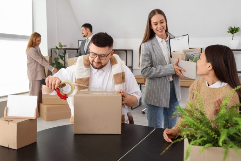 A group of employees packs up their office into boxes.